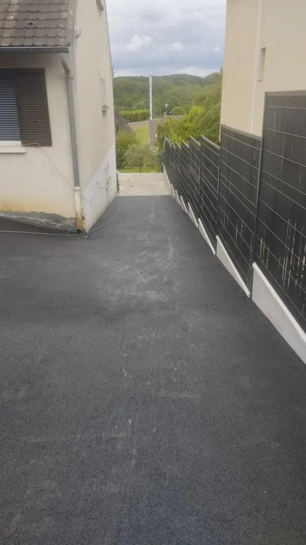 Allée étroite en enrobé noir le long d'une maison