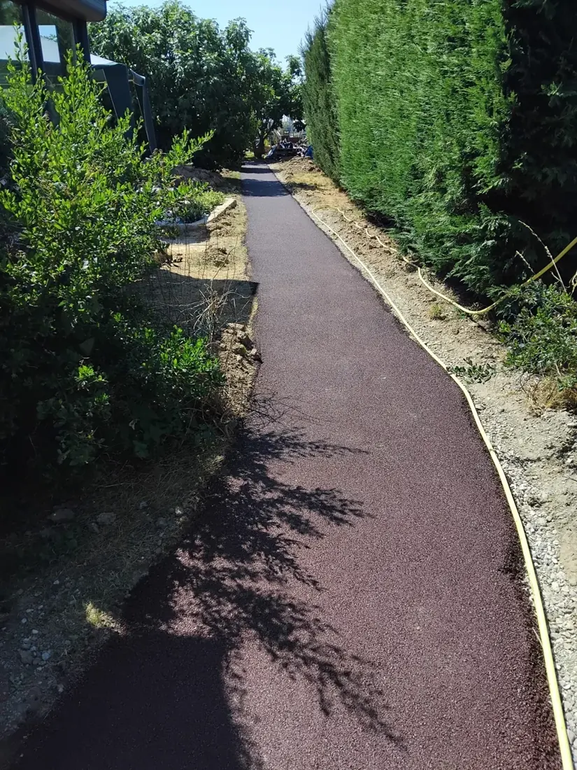 Chemin en enrobé rouge dans un jardin